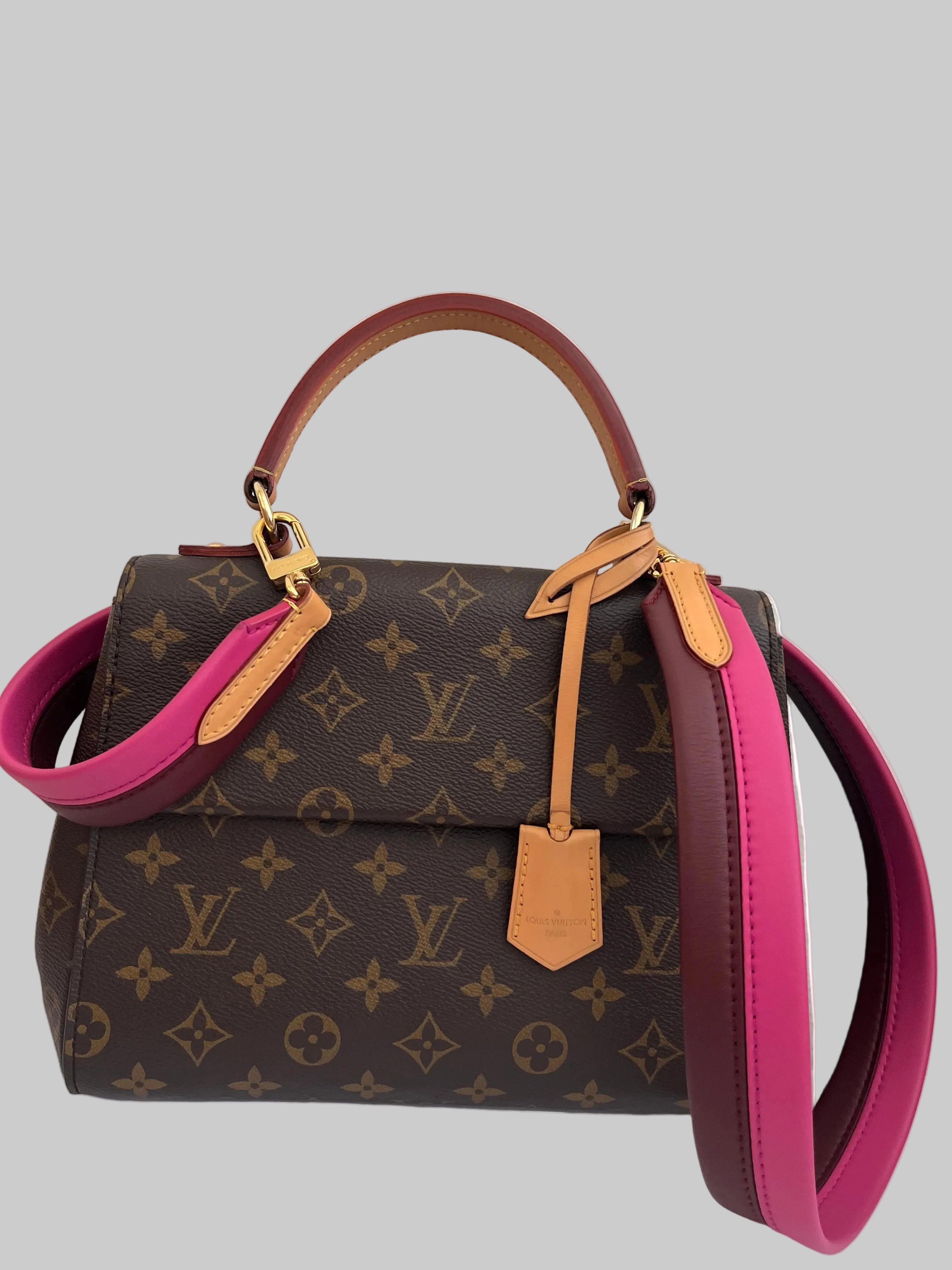 Designer handbag with monogram pattern and pink accents on a white background